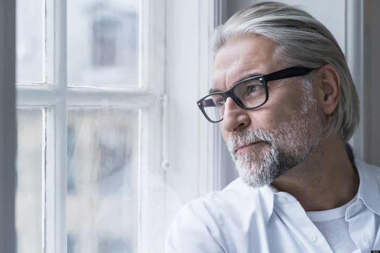Mature man with glasses looking out of window