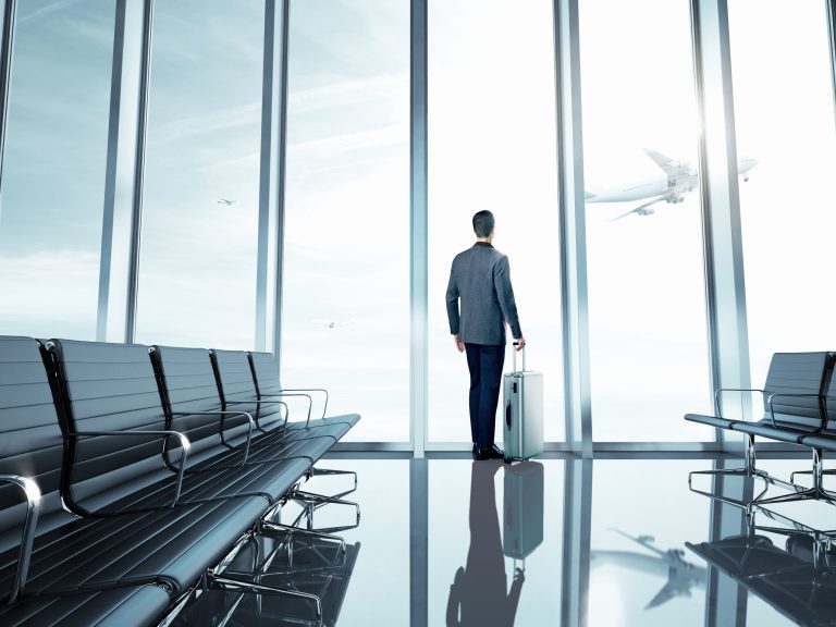 Business man standing at airport with suitcase.